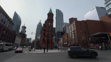 Gooderham Binası 'nın nefes kesici 4K görüntüsü açık mavi gökdelenlerin altında modern gökdelenlerin arka planına karşı çekilmiştir. Güneşli bir gün, tarihsel tuğla yapı arasındaki zıtlığı arttırır.