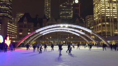 Kanada, Ontario, Toronto 'daki Nathan Phillips Civic Meydanı' ndaki belediye binasının önündeki halk buz pateni pistinde 4K 'lık bir çekim. Sahne, kışın neşeli atmosferini yakalar.