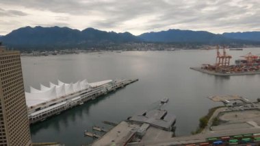 Bulutlu bir günde Vancouver 'ın 4K' lık zaman çizelgesi. Boğaz boyunca giden gemiyi yakalıyor. Çekim, Kanada 'nın ikonik mekanını, uzaktaki yüksek dağları ve hareket halindeki iskele vinçlerini içeriyor.