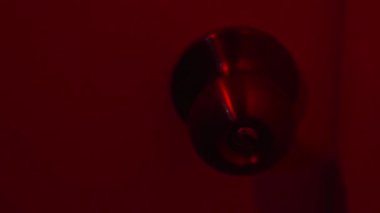 Kapı kolu yanıp sönen kırmızı ışıkta kıvrılır, duvarlar boyunca uzamış gölgeler bırakır. Kapı yavaşça gıcırdarken loş kıpkırmızı parıltı odayı dolduruyor ve rahatsız edici bir atmosfer yaratıyor. Şey...