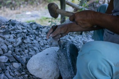Ormanda kürekle dolaşan siyah tişörtlü adam.