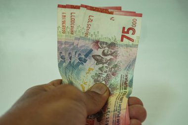 Eldeki para, Endonezya parası 75 bin rupi.