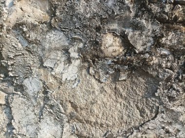 Çürüme ve erozyon belirtileri gösteren sert ve dokulu bir duvar yüzeyi. Yıpranmış taş, zamanın, dayanıklılığın ve doğal giyimin hikayesini anlatıyor..