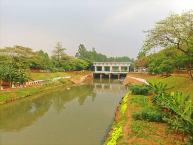 Jakarta 'daki Banjir Kanal Timur (BKT), bereketli yeşillik ve sakin bir su yolu ile çevrili, kentsel ve çevresel sürdürülebilirliği güvence altına alan hayati bir sel kontrol altyapısıdır..