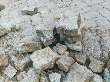 Toprak ve molozlarla çevrili bir tuğla yığını yerde yatıyor.