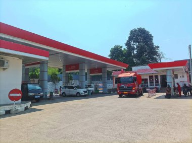 Bogor, Endonezya - 28 Eylül 2024: Güneşli gökyüzünün altındaki bir benzin istasyonunda yakıt ikmali için hazır parlak kırmızı bir Pertamina yakıt kamyonu, verimli enerji dağıtımını vurguluyor.