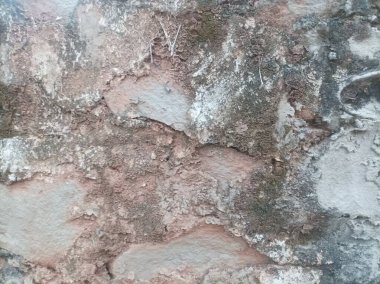 Yıpranmış ve desenli bu taş duvar zamanın pürüzlü, düzensiz yüzeyinden geçişini gösteriyor. Toprak tonlarını doğal aşınmayla harmanlıyor..