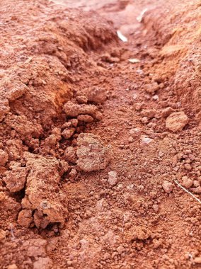 Kuru, kırmızımsı toprak siperinin yakın görüntüsü toprak dokularını ve engebeli yüzeyini aydınlatarak doğanın saf güzelliğini yansıtıyor..