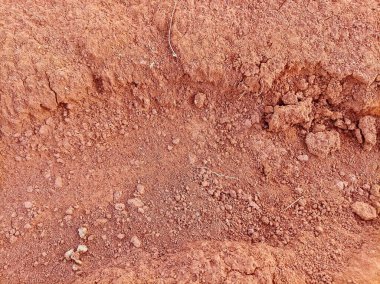 Kuru, kırmızımsı toprak siperinin yakın çekim görüntüsü toprak dokularını ve engebeli yüzeyi aydınlatıyor..