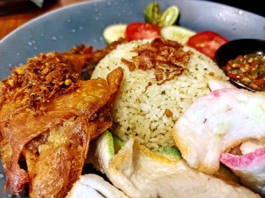 Lezzetli bir tabak kızarmış tavuk, mis kokulu pilav, çıtır kraker ve sambal ile servis edilen taze sebzeler, lezzet ve dokulardan oluşan bir ziyafet..