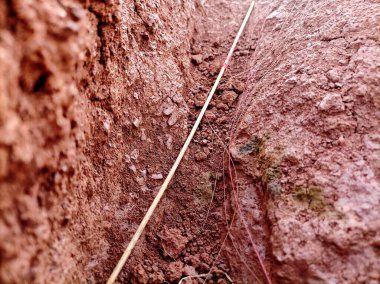 Kırmızı toprak siperinin yakın çekimi, ham toprak dokusunu ve doğal oluşumunu gözler önüne seriyor, sert ve organik güzelliğini vurguluyor..