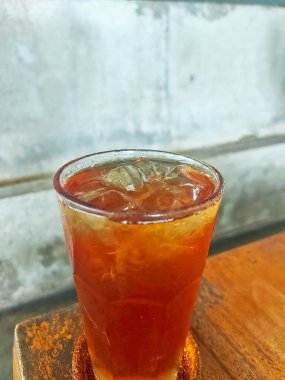 A refreshing glass of iced tea served on a rustic wooden table, perfect for cooling down and enjoying a moment of tranquility. clipart