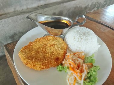 Tüylü beyaz pirinç, lezzetli soya sosu ve taze lahana salatasıyla servis edilen çıtır tavuk katsusu mükemmel bir lezzet ve doku dengesi sağlar..