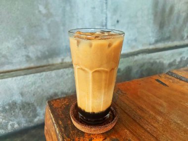 Kahverengi şekerli buzlu kahve, kremalı latte, serin bir canlandırıcı için mükemmel, berrak bir bardakta servis ediliyor, kırsal cazibeyle..