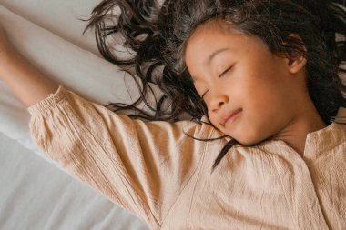 A serene capture of a young girl peacefully asleep, radiating calmness, innocence, and warmth in the gentle glow of natural light. clipart