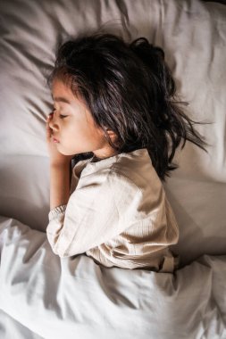 Uyuyan bir çocuğun huzurlu bir anı. Yumuşak çarşaflara sarılı. Huzurlu ve rahat bir atmosferde sıcaklık ve sükunet yayıyor..