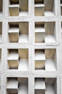 Geometrik beton bloklar yinelenen bir desen oluşturarak dokulu yüzey üzerinde ışık ve gölge etkileşimi ile çarpıcı bir görsel etki yaratır..