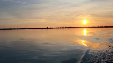 Gölün üzerinde gün batımı, akşam gökyüzü, güneş suya yansıyor..