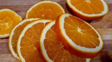 Olgun portakal ve portakal dilimleri koyu ahşap bir masada.