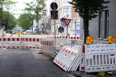 Kırmızı ve beyaz çizgili dikey uyarı kalınlıkları, tabelaları, bariyerleri, geçici metal çitleri olan sokak onarım sahası.