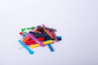 Renkli ortodontik bağlar, tedavi sırasında düzgün diş hizalanması ve istikrarın sağlanması için, parantezlere kemer telleri yerleştirmek üzere tasarlandı..