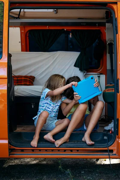 Two brothers fighting over the tablet on a wonderful day camping in a van. Van life concept.