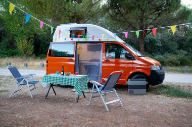 Kamp aracı tarlada, sandalyeli ve dinlenme masalı. van life konsepti .