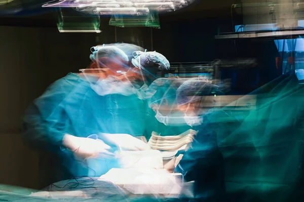 Motion photography with slow exposure of the doctor with mask doing a surgery. Emergency effect.