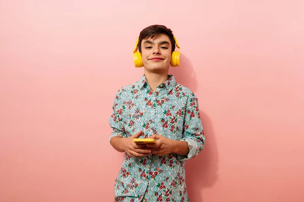 Νεαρός Που Χρησιμοποιεί Smartphone Και Κίτρινα Ακουστικά Στο Στούντιο Ροζ — Φωτογραφία Αρχείου