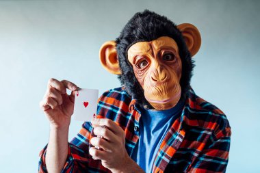 Maymun maskesi takan ve elinde poker kartları tutan bir adam..