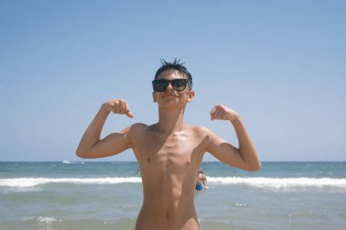 Genç kız sahilde muhteşem bir günün tadını çıkarıyor. Güçlü kollarını gösteriyor..