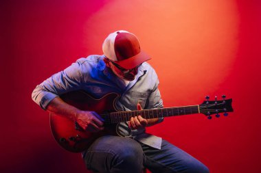 Kırmızı arkaplanda elektro gitar çalan adam