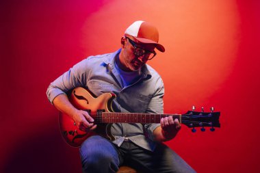 Kırmızı arkaplanda elektro gitar çalan adam