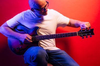 Kırmızı arkaplanda elektro gitar çalan adam