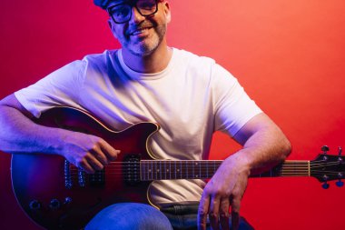 Kırmızı arkaplanda elektro gitar çalan adam