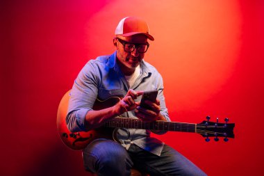 Kırmızı arkaplanda elektro gitar çalan adam