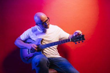 Kırmızı arkaplanda elektro gitar çalan adam