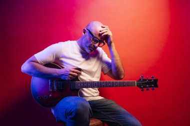 Kırmızı arkaplanda elektro gitar çalan adam