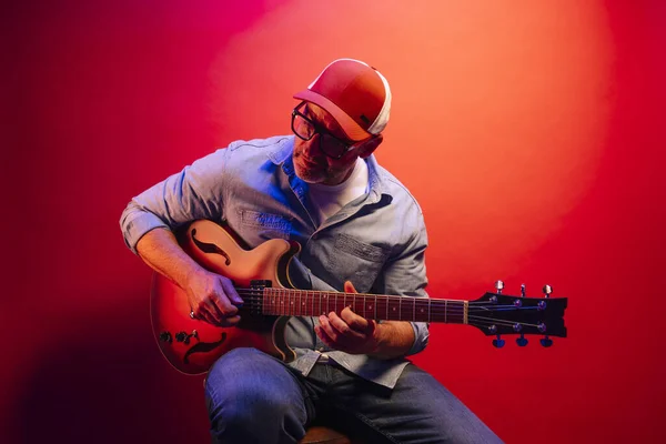 在红色背景下弹奏电吉他的人 — 图库照片