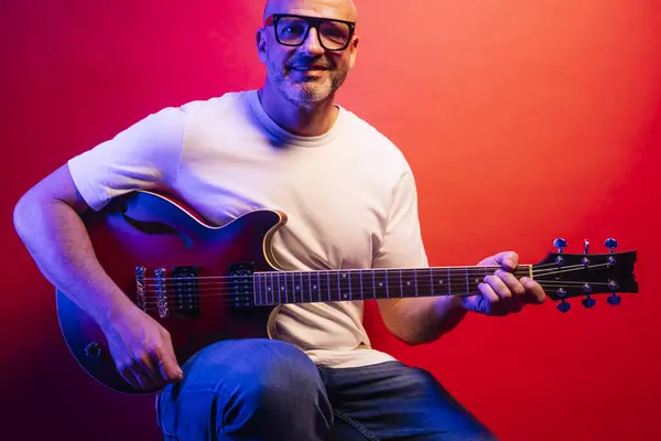 Mann Spielt Gitarre Auf Rotem Hintergrund — Stockfoto