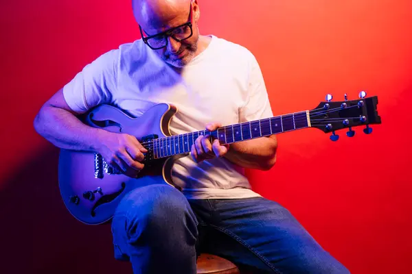 Man playing electric guitar on red background