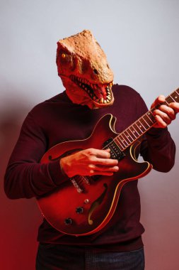 Stüdyoda kertenkele kafalı ve elektro gitarlı bir adam var..