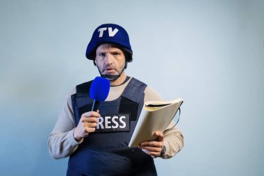 Stüdyoda mikrofon tutan kurşun geçirmez yelek giyen bir muhabir..