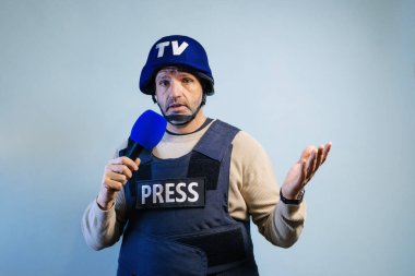 Stüdyoda mikrofon tutan kurşun geçirmez yelek giyen bir muhabir..