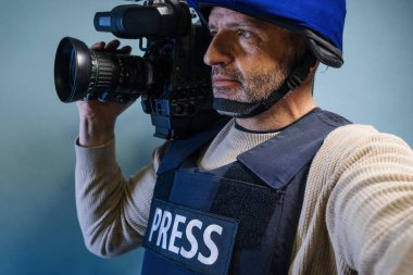 Elinde video kamera tutan kurşun geçirmez yelek giyen bir muhabir.