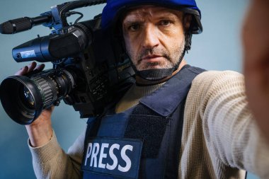 Elinde video kamera tutan kurşun geçirmez yelek giyen bir muhabir.