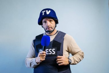 Stüdyoda mikrofon tutan kurşun geçirmez yelek giyen bir muhabir..