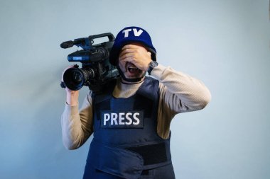 Elinde video kamera tutan kurşun geçirmez yelek giyen bir muhabir.