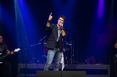 Canlı bir konserde seyircilerin önünde şarkı söyleyen sanatçı.