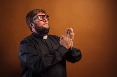 Haçlı ve siyah gömlekli bir rahibin portresi dua ediyor..